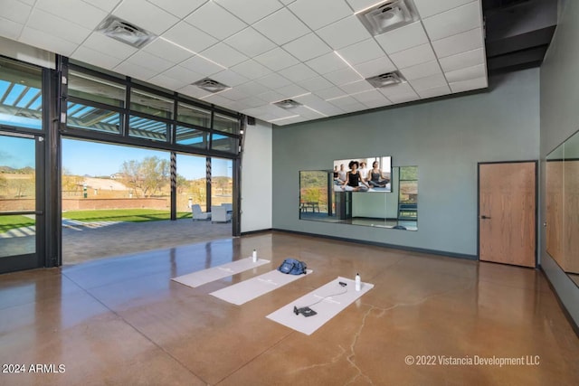 interior space featuring concrete flooring, baseboards, visible vents, and a high ceiling