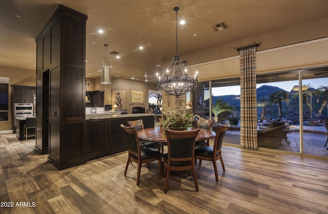 dining space with a mountain view, a notable chandelier, and hardwood / wood-style flooring