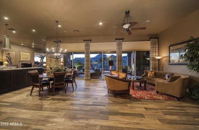 interior space with ceiling fan with notable chandelier and hardwood / wood-style flooring