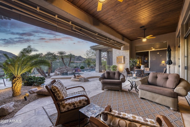 patio terrace at dusk with ceiling fan and an outdoor living space with a fire pit