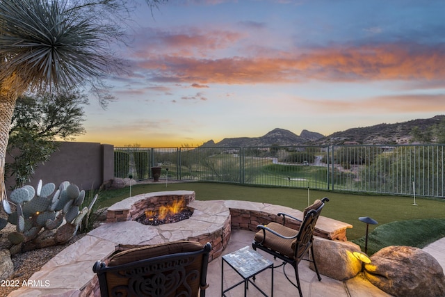 patio terrace at dusk featuring a mountain view and an outdoor fire pit