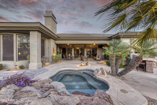 pool at dusk featuring a patio area and a hot tub