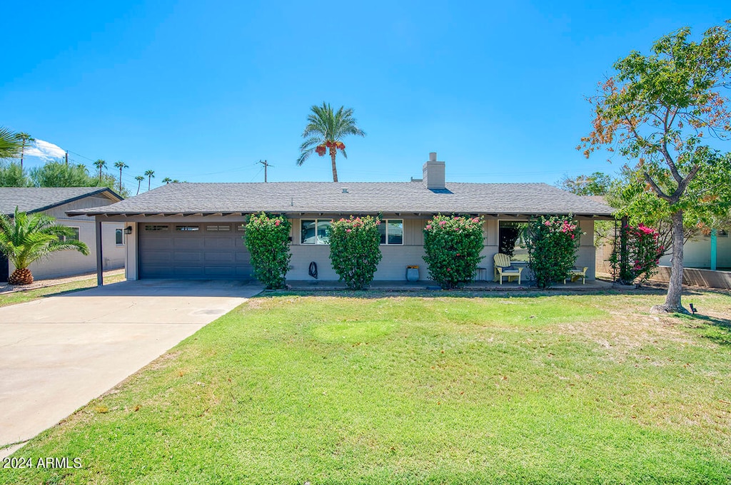 ranch-style home with a garage and a front lawn