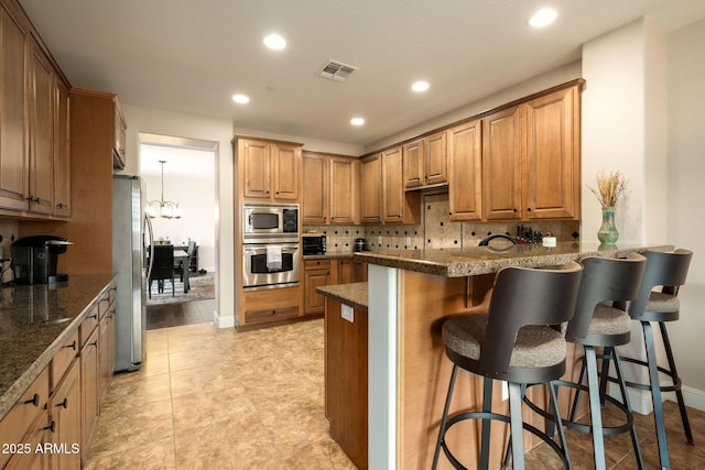 17665 N 93rd Way, Scottsdale, AZ 85255 - kitchen featuring stainless steel appliances, a peninsula, a breakfast bar, decorative backsplash, and recessed lighting
