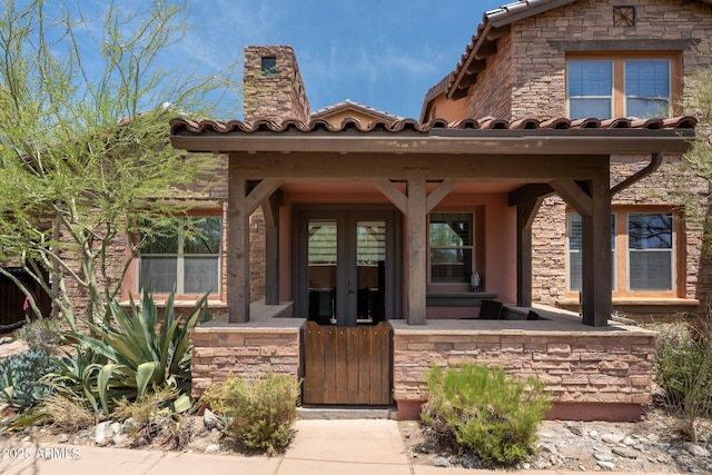 17665 N 93rd Way, Scottsdale, AZ 85255 - view of exterior entry with french doors, stone siding, a tile roof, and a chimney