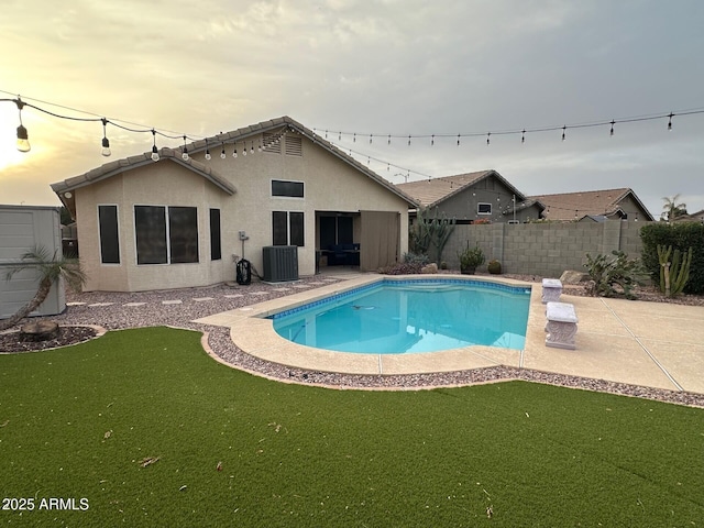 view of swimming pool with a patio, a yard, cooling unit, and a fenced backyard