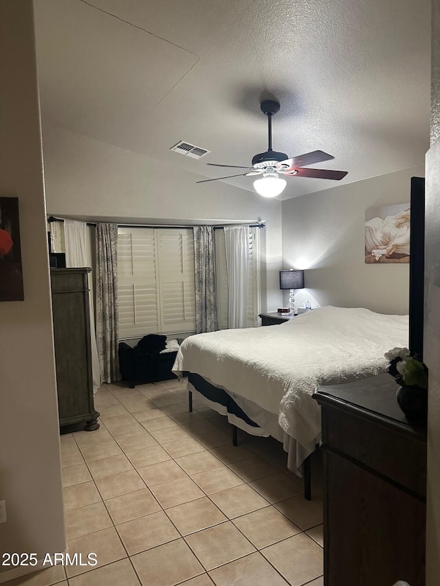 bedroom featuring light tile patterned floors, ceiling fan, a textured ceiling, lofted ceiling, and visible vents