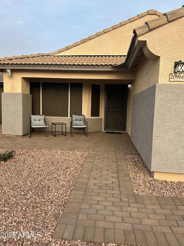 property entrance with a patio and stucco siding