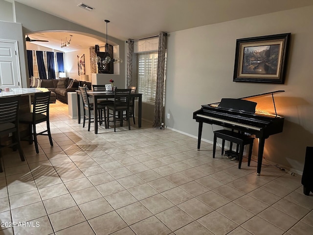 dining room featuring arched walkways, light tile patterned flooring, visible vents, baseboards, and vaulted ceiling