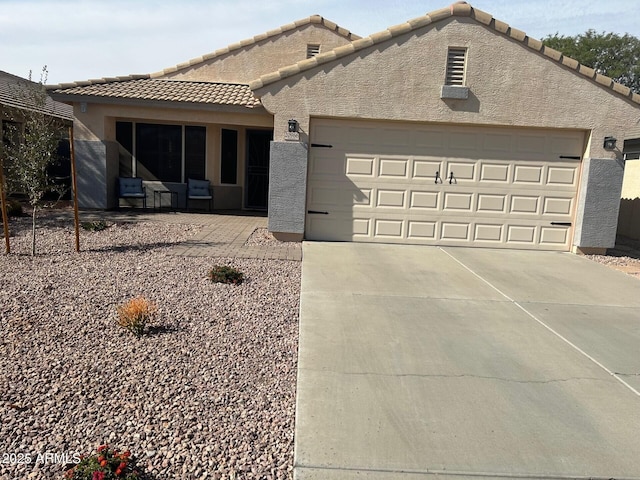 view of front of home with a garage, a tile roof, concrete driveway, and stucco siding