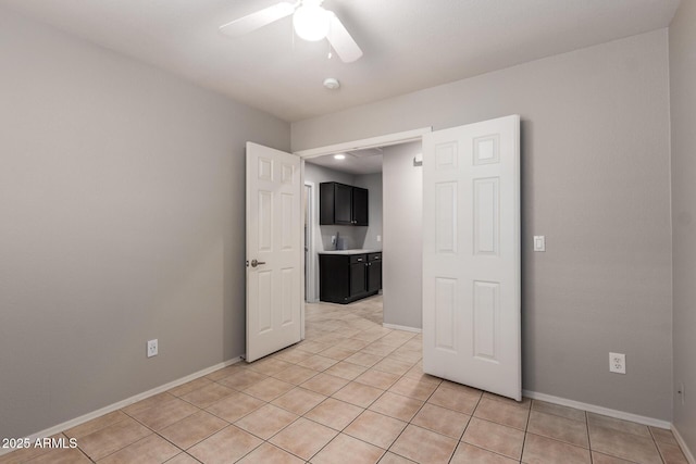 spare room featuring light tile patterned flooring, ceiling fan, and baseboards