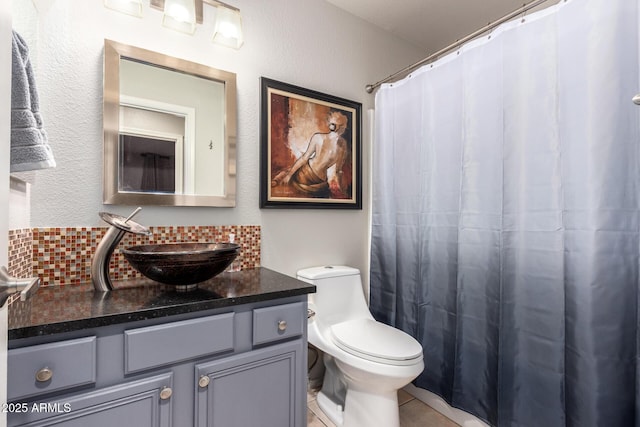 bathroom featuring tile patterned flooring, toilet, a shower with shower curtain, vanity, and backsplash