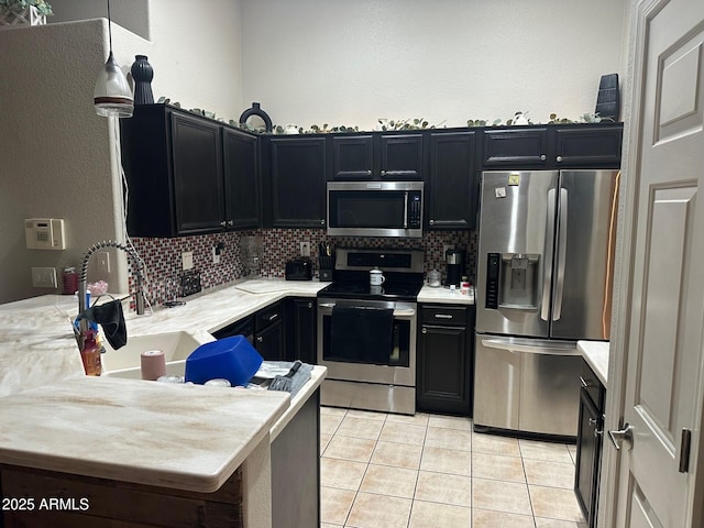 kitchen featuring appliances with stainless steel finishes, light tile patterned flooring, dark cabinetry, and decorative backsplash