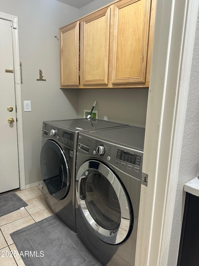 clothes washing area with light tile patterned floors, cabinet space, and washer and dryer