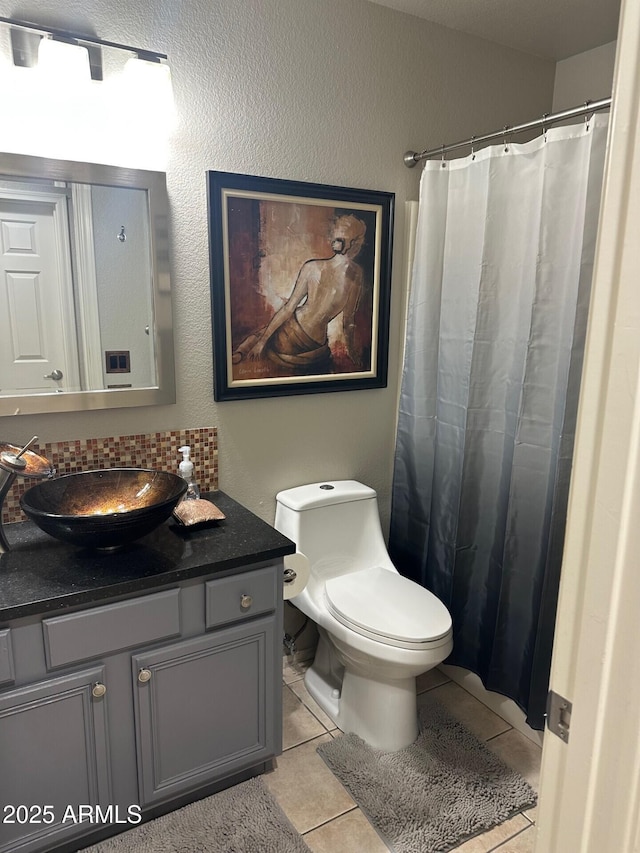 bathroom featuring tile patterned flooring, toilet, a shower with shower curtain, vanity, and tasteful backsplash