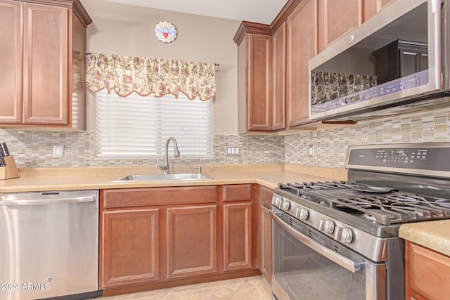 kitchen featuring backsplash, light tile patterned floors, sink, and appliances with stainless steel finishes