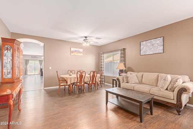 living room with ceiling fan and dark wood-type flooring