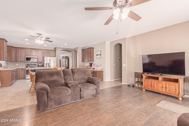 living room featuring ceiling fan, light hardwood / wood-style floors, and sink