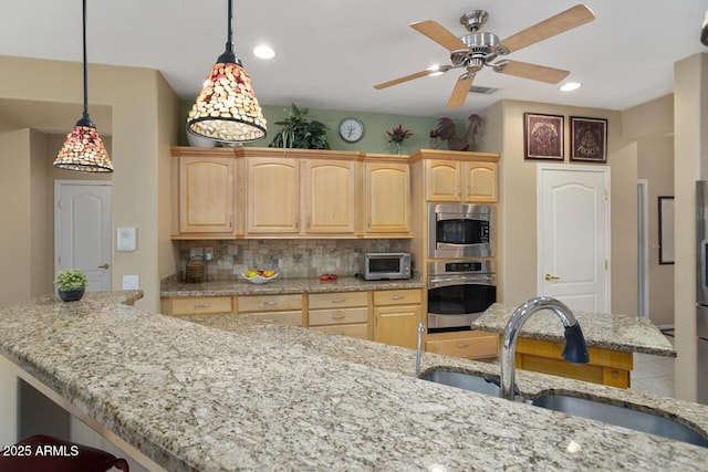 kitchen with appliances with stainless steel finishes, tasteful backsplash, sink, hanging light fixtures, and light brown cabinets