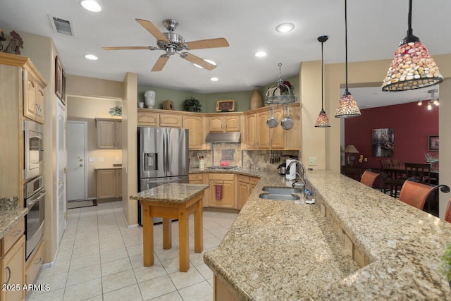 kitchen with appliances with stainless steel finishes, decorative light fixtures, sink, decorative backsplash, and light stone counters