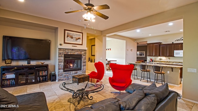 living room with a stone fireplace and ceiling fan