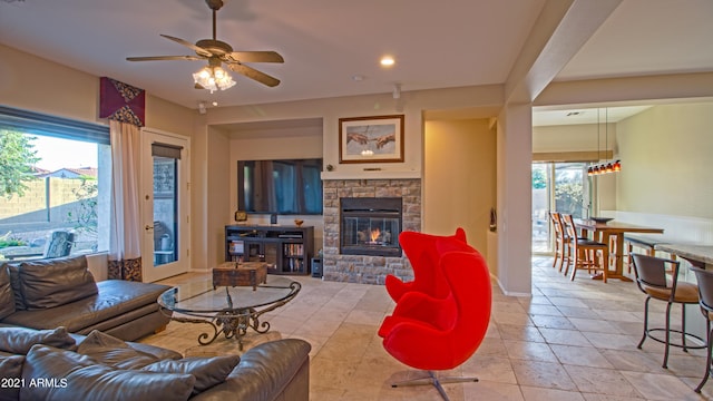 living room featuring a stone fireplace and ceiling fan