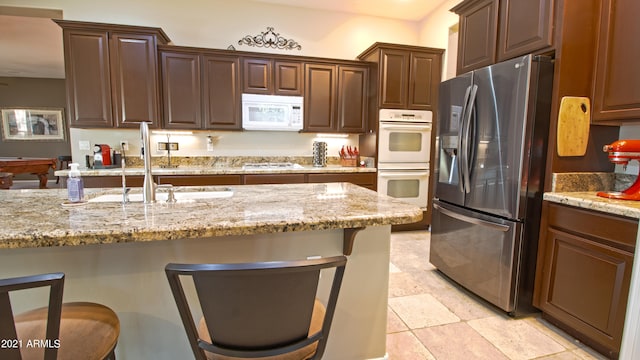 kitchen featuring light stone countertops, appliances with stainless steel finishes, sink, and a kitchen bar