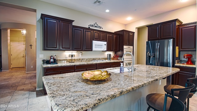 kitchen with sink, a kitchen island with sink, stainless steel appliances, and a breakfast bar