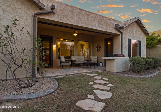 back house at dusk featuring a patio, ceiling fan, and a lawn