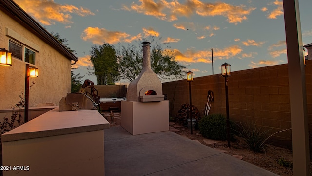 patio terrace at dusk featuring grilling area and exterior kitchen