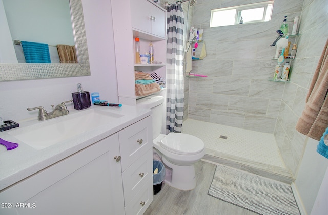 bathroom with hardwood / wood-style floors, toilet, vanity, and curtained shower