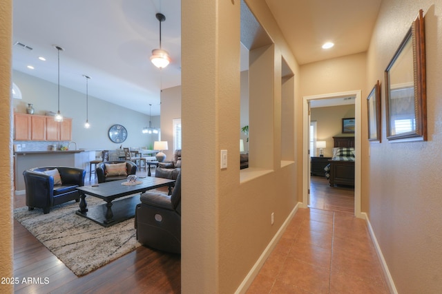 hall with visible vents, baseboards, wood finished floors, high vaulted ceiling, and recessed lighting