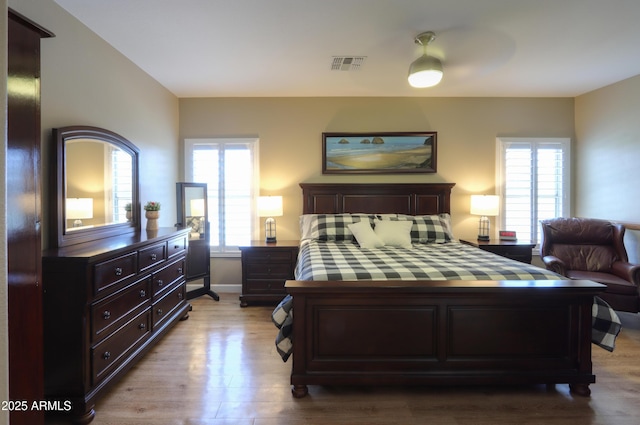 bedroom featuring light wood-type flooring, baseboards, and visible vents