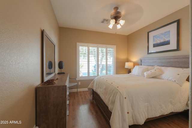 bedroom featuring ceiling fan, wood finished floors, visible vents, and baseboards