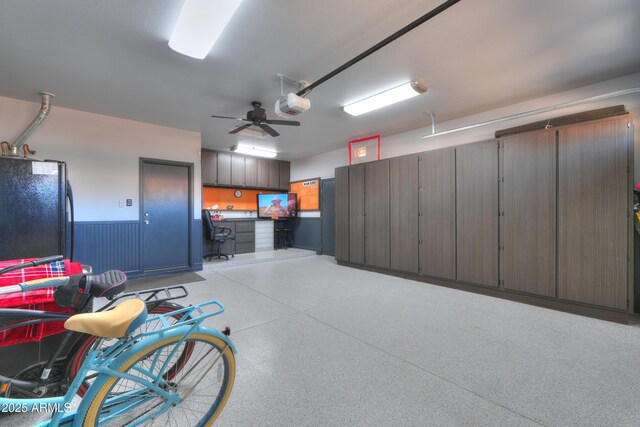 garage featuring ceiling fan, wainscoting, freestanding refrigerator, and a garage door opener