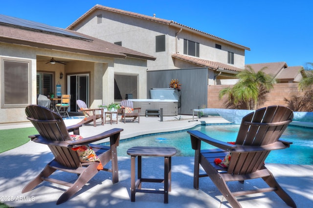 rear view of house with a hot tub, a patio, ceiling fan, a fenced backyard, and stucco siding