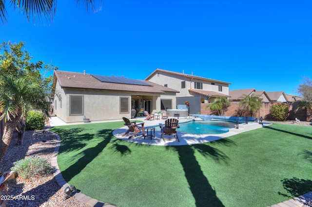 back of house with a fenced backyard, a jacuzzi, solar panels, a fenced in pool, and stucco siding