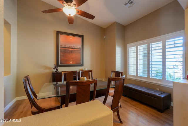 dining space with lofted ceiling, light wood-style flooring, a ceiling fan, visible vents, and baseboards