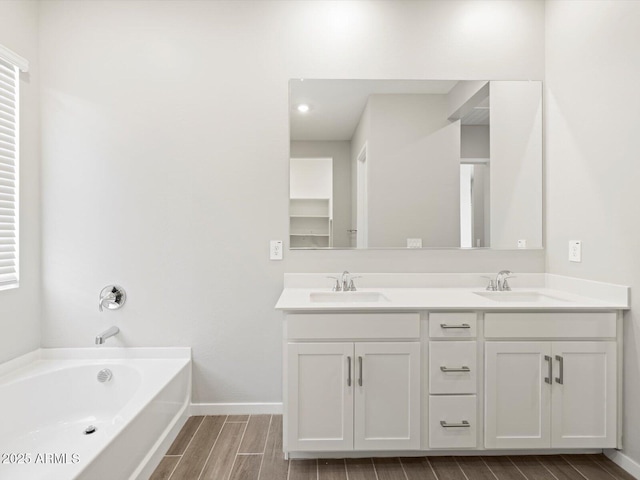 17561 W Pierson St, Goodyear, AZ 85395 - bathroom featuring wood tiled floors, double vanity, a bath, and baseboards