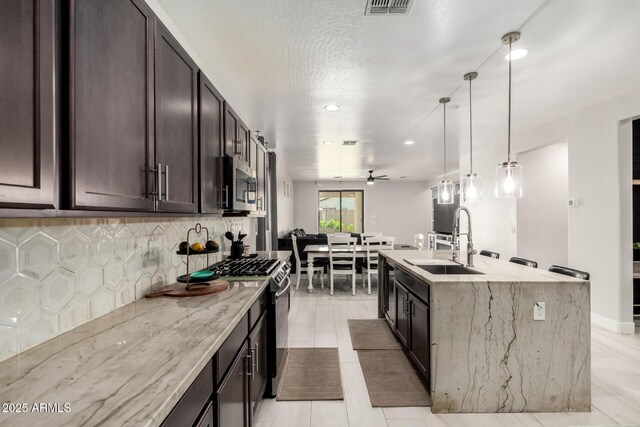 3715 S 57th Ln, Phoenix, AZ 85043 - kitchen with black range with gas stovetop, stainless steel microwave, a ceiling fan, decorative backsplash, and dark brown cabinets