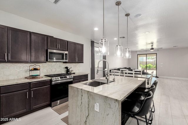 3715 S 57th Ln, Phoenix, AZ 85043 - kitchen featuring stainless steel appliances, backsplash, a ceiling fan, open floor plan, and light stone countertops