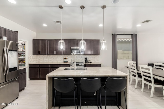 3715 S 57th Ln, Phoenix, AZ 85043 - kitchen with appliances with stainless steel finishes, tasteful backsplash, a kitchen bar, dark brown cabinets, and recessed lighting