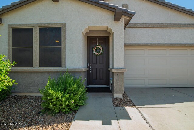 3715 S 57th Ln, Phoenix, AZ 85043 - doorway to property featuring stucco siding, an attached garage, and concrete driveway
