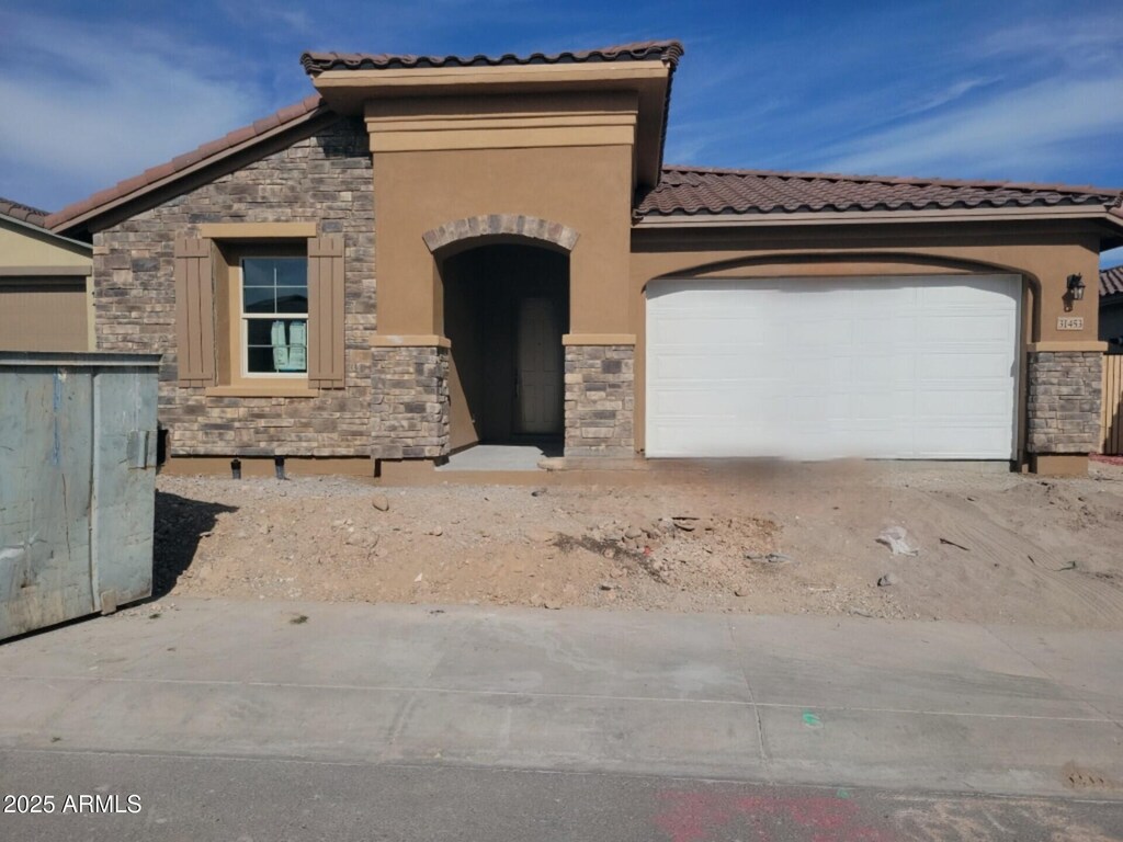 31453 N 130th Ave, Peoria, AZ 85383 - mediterranean / spanish-style house featuring stone siding, a tile roof, an attached garage, and stucco siding