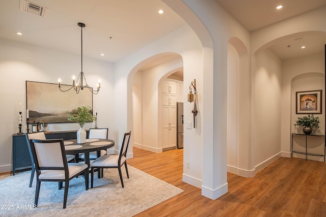 dining area with hardwood / wood-style flooring and a notable chandelier