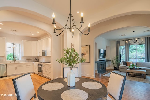 dining room with a notable chandelier, sink, and light hardwood / wood-style flooring