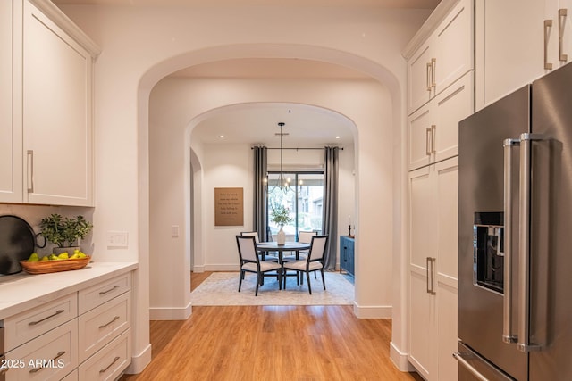 kitchen featuring white cabinetry, pendant lighting, light hardwood / wood-style flooring, and high end refrigerator