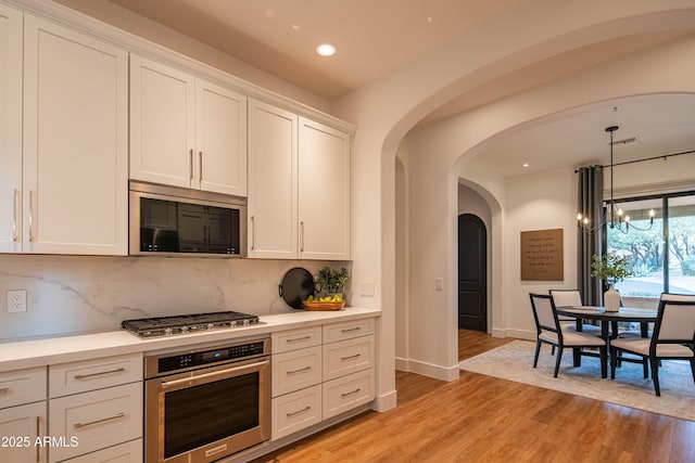 kitchen featuring appliances with stainless steel finishes, decorative backsplash, light hardwood / wood-style flooring, and white cabinetry