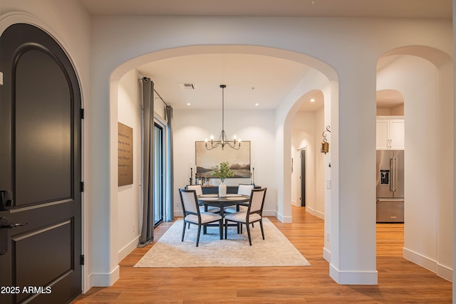 dining room with light hardwood / wood-style flooring and an inviting chandelier