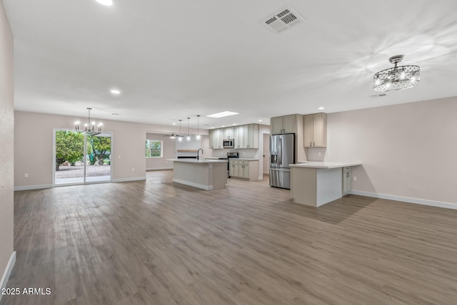 kitchen with decorative light fixtures, sink, stainless steel appliances, and light wood-type flooring